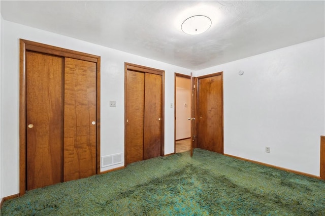unfurnished bedroom featuring two closets, visible vents, carpet flooring, and baseboards