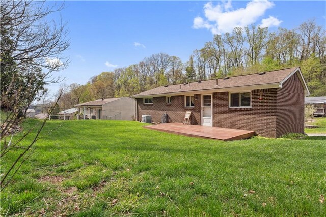rear view of property with brick siding, a lawn, a wooden deck, and central AC unit