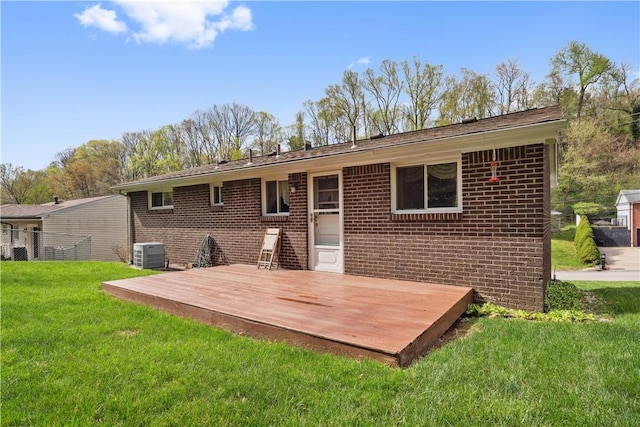 back of property with brick siding, a yard, central AC, and a deck