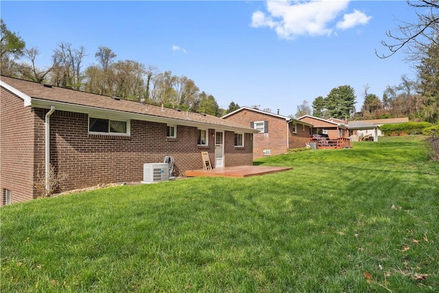 rear view of property featuring brick siding, a lawn, central AC, and a patio