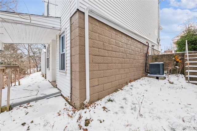 snow covered property with central AC unit