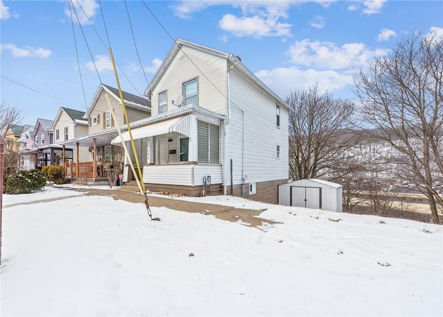 snow covered property featuring a garage, covered porch, and an outdoor structure