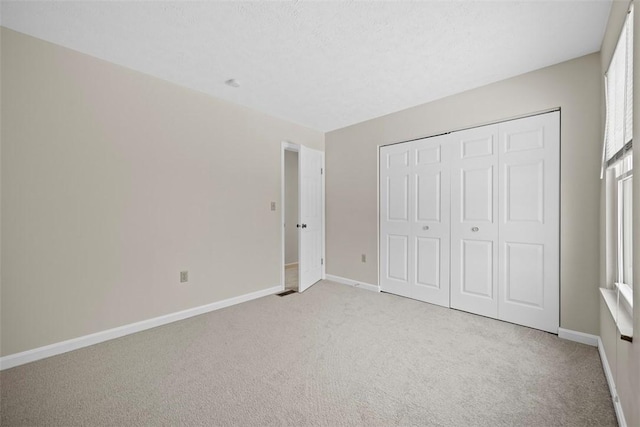 unfurnished bedroom featuring light colored carpet and a closet