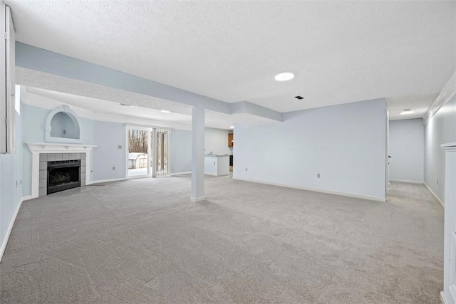 basement with a tiled fireplace, light colored carpet, and a textured ceiling