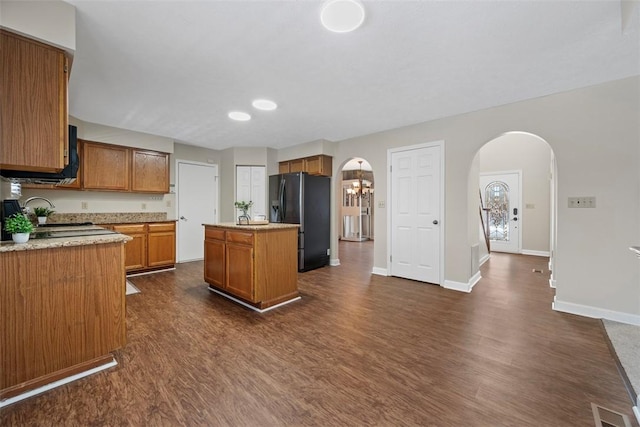 kitchen featuring black refrigerator with ice dispenser, a center island, dark hardwood / wood-style floors, and sink