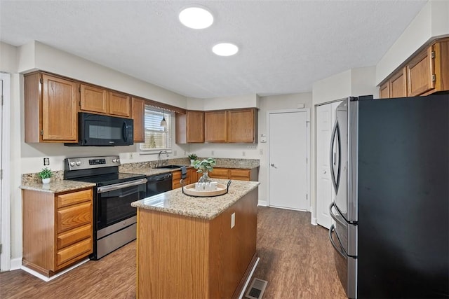 kitchen with hardwood / wood-style floors, black appliances, sink, a textured ceiling, and a kitchen island