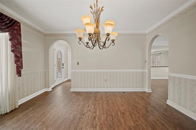 unfurnished dining area featuring a notable chandelier, ornamental molding, and dark wood-type flooring