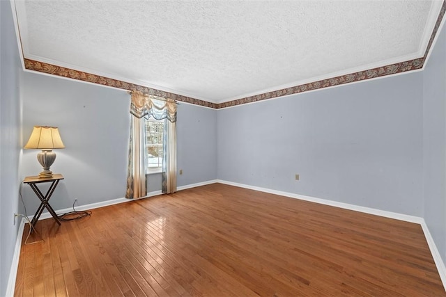 empty room with wood-type flooring, a textured ceiling, and ornamental molding