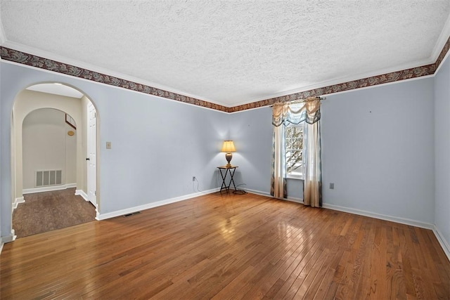 empty room featuring hardwood / wood-style floors, a textured ceiling, and ornamental molding