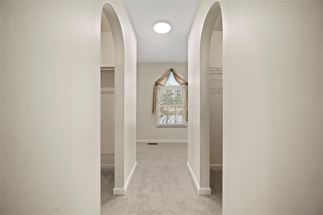 hall with light carpet and a textured ceiling