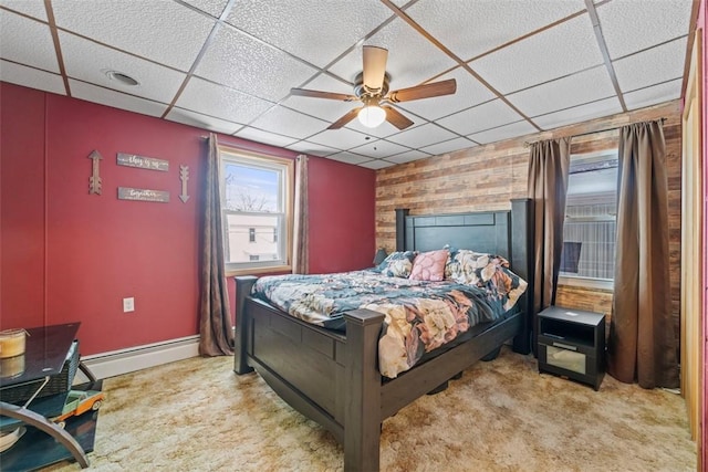 bedroom featuring a paneled ceiling, ceiling fan, wood walls, and a baseboard radiator