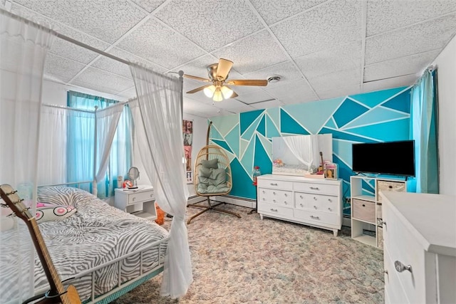 bedroom with a drop ceiling, carpet floors, baseboard heating, and ceiling fan