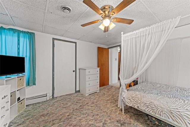 bedroom with a paneled ceiling, ceiling fan, carpet floors, and a baseboard heating unit