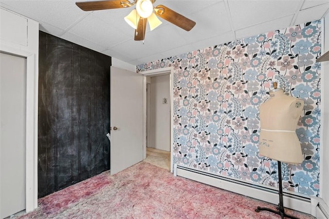 carpeted bedroom with a paneled ceiling, a baseboard radiator, and ceiling fan