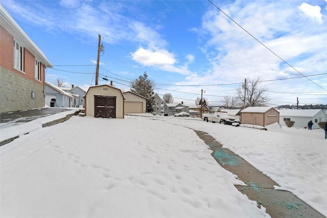 yard layered in snow with a shed and a garage