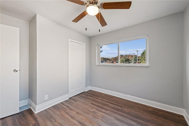 unfurnished bedroom with ceiling fan, dark wood-type flooring, and a closet