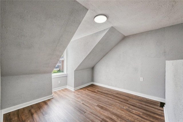 additional living space with hardwood / wood-style floors and lofted ceiling