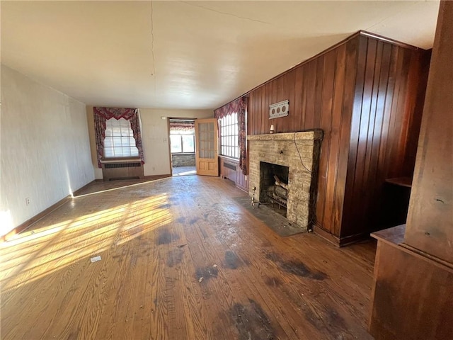 unfurnished living room with wood-type flooring, a fireplace, and radiator