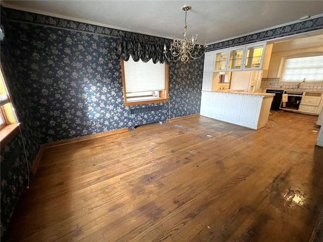 unfurnished dining area featuring a chandelier, sink, radiator, and hardwood / wood-style floors