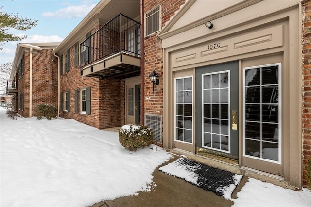 snow covered property entrance with a balcony