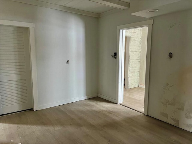 spare room featuring beam ceiling and light wood-type flooring