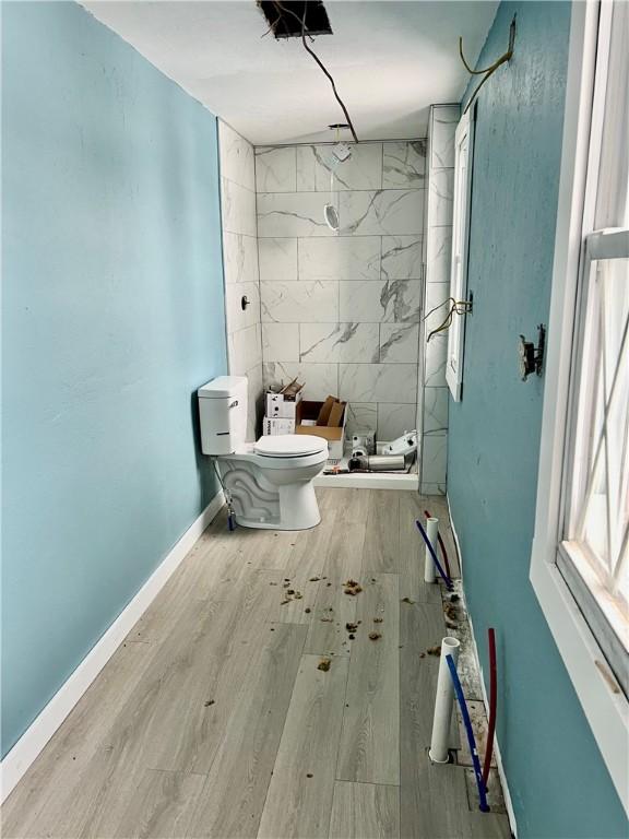 bathroom featuring toilet, wood-type flooring, and a shower