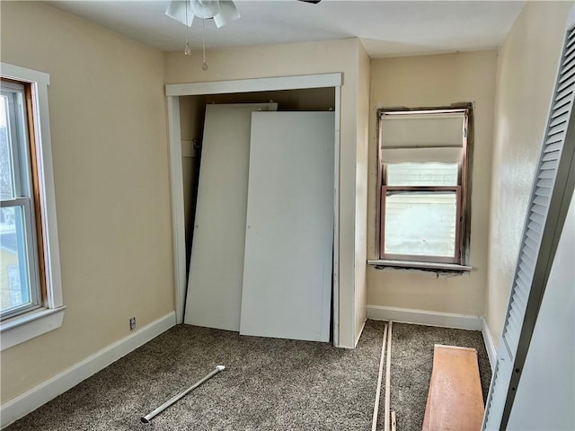 unfurnished bedroom featuring multiple windows, a closet, and dark carpet