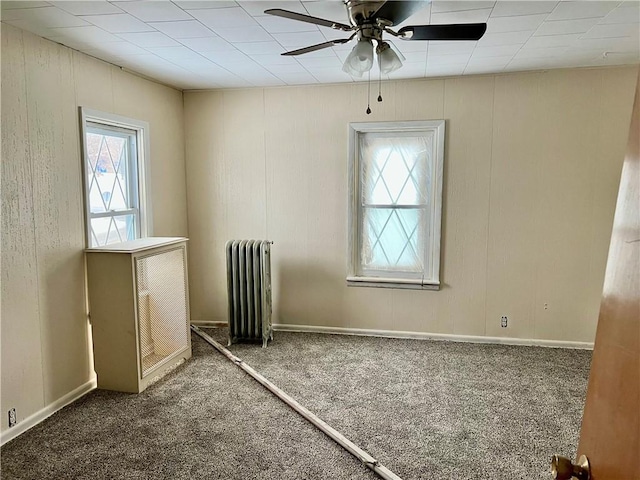 carpeted empty room with radiator and ceiling fan