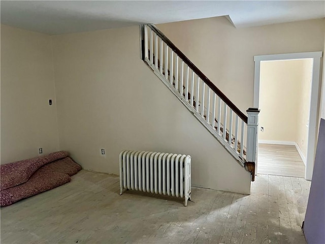 stairs featuring radiator heating unit and wood-type flooring