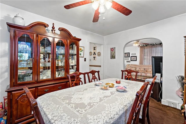 dining space featuring ceiling fan and dark carpet