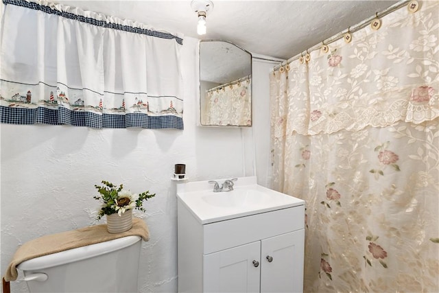 bathroom with a textured ceiling, toilet, and vanity