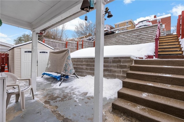 snow covered patio featuring a storage unit