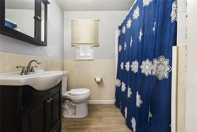 bathroom featuring vanity, wood-type flooring, tile walls, and toilet