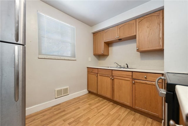 kitchen featuring stove, light hardwood / wood-style flooring, and sink