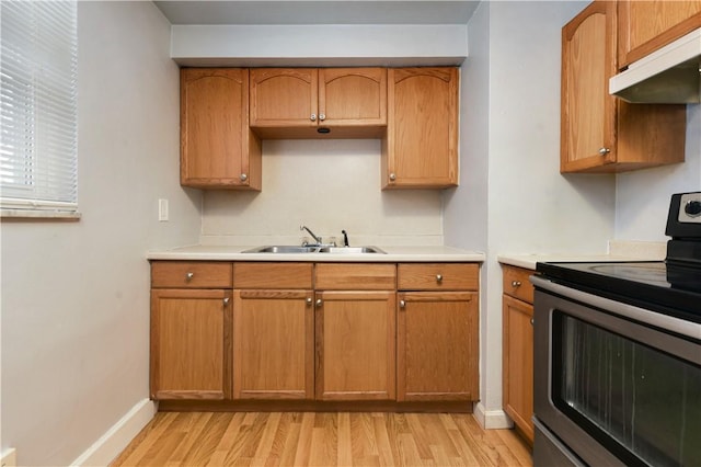 kitchen with light wood-type flooring, stainless steel electric stove, and sink