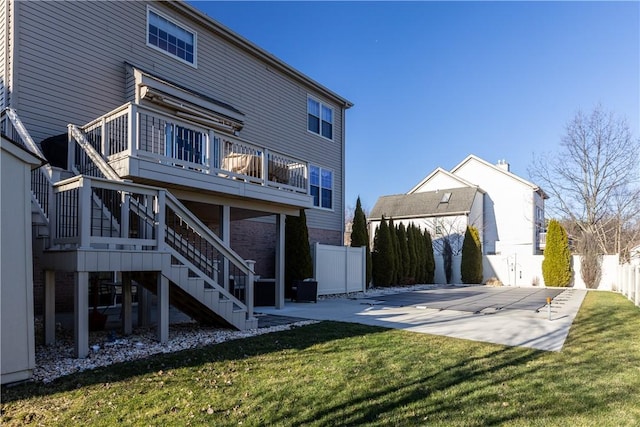 back of property with a deck, a patio area, and a lawn