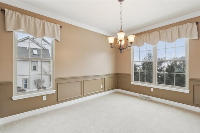 carpeted empty room featuring crown molding and an inviting chandelier