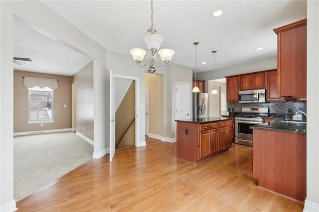 kitchen featuring a kitchen island, decorative light fixtures, backsplash, light hardwood / wood-style floors, and stainless steel appliances