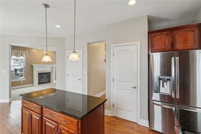 kitchen featuring pendant lighting, dark stone counters, stainless steel fridge, and light hardwood / wood-style flooring