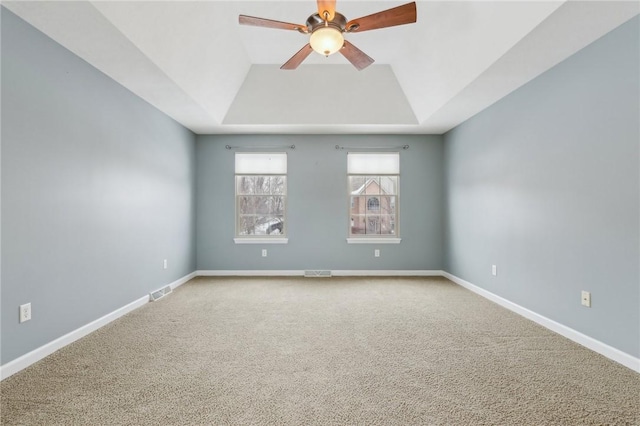 carpeted empty room with ceiling fan and a tray ceiling