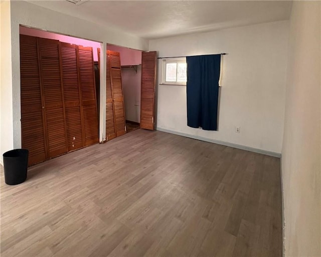 unfurnished bedroom featuring hardwood / wood-style floors and two closets