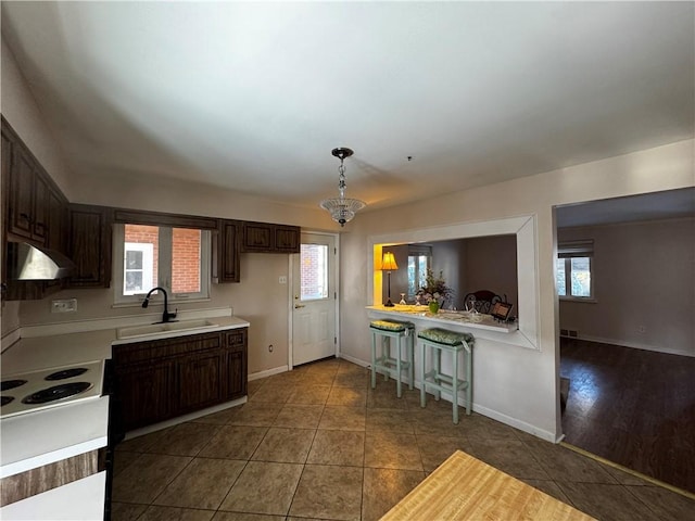 kitchen featuring sink, pendant lighting, dark tile patterned flooring, and dark brown cabinetry