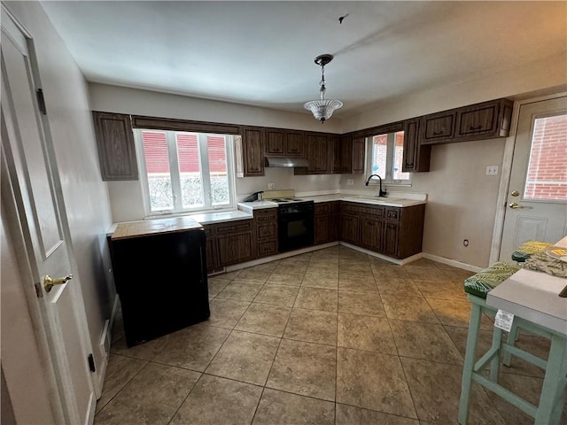 kitchen with pendant lighting, black electric range oven, light tile patterned flooring, and a wealth of natural light