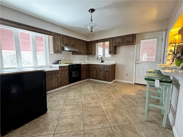 kitchen featuring light tile patterned floors, decorative light fixtures, sink, and black appliances