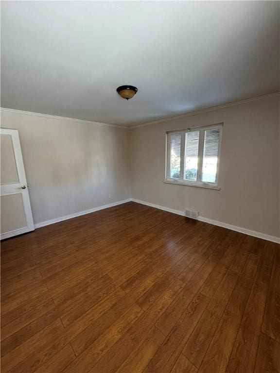 spare room with dark wood-type flooring and ornamental molding