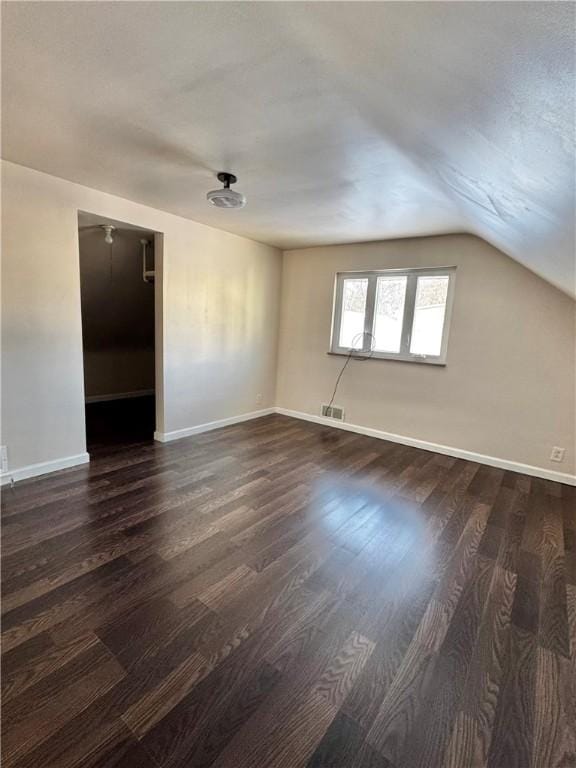 additional living space featuring dark wood-type flooring and vaulted ceiling