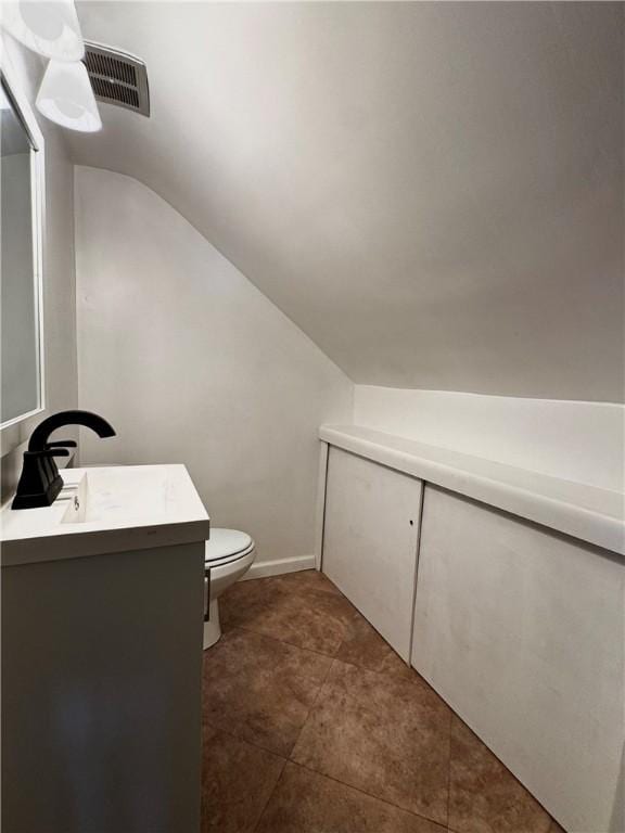 bathroom featuring vanity, vaulted ceiling, and toilet