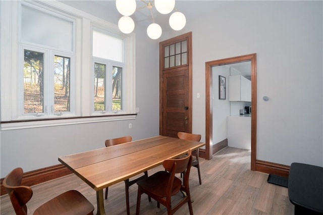 dining area featuring light wood-type flooring and a notable chandelier