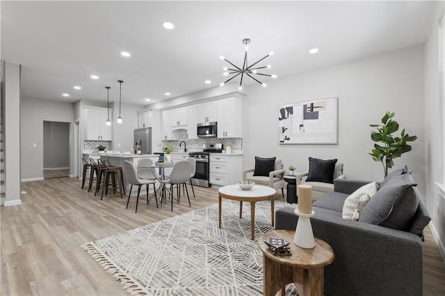 living room with light wood-type flooring, sink, and an inviting chandelier