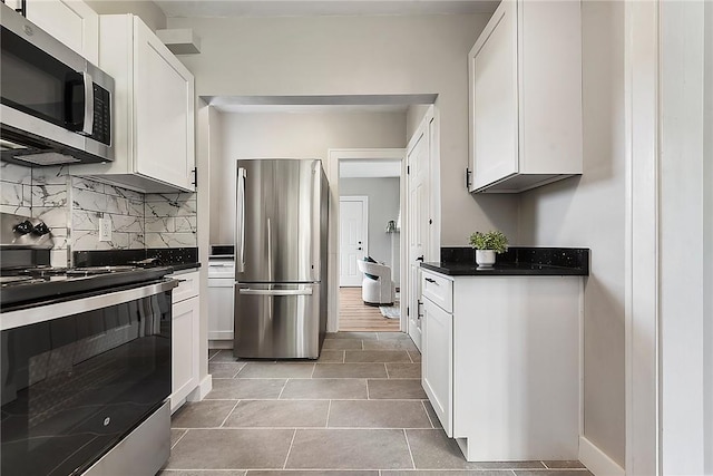 kitchen featuring white cabinets, appliances with stainless steel finishes, decorative backsplash, and light tile patterned floors